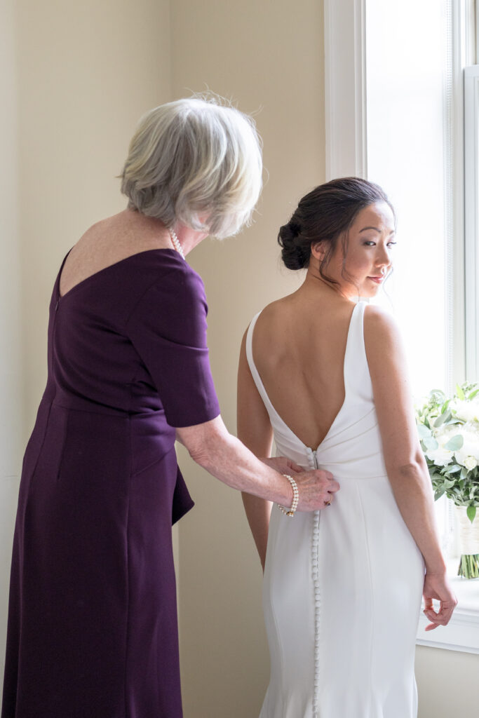 Bride getting ready details - Mom zipping up the dress