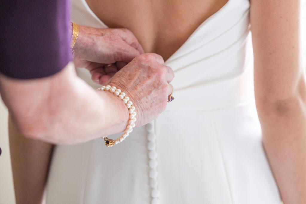 Bride getting ready details - Mom zipping up the dress