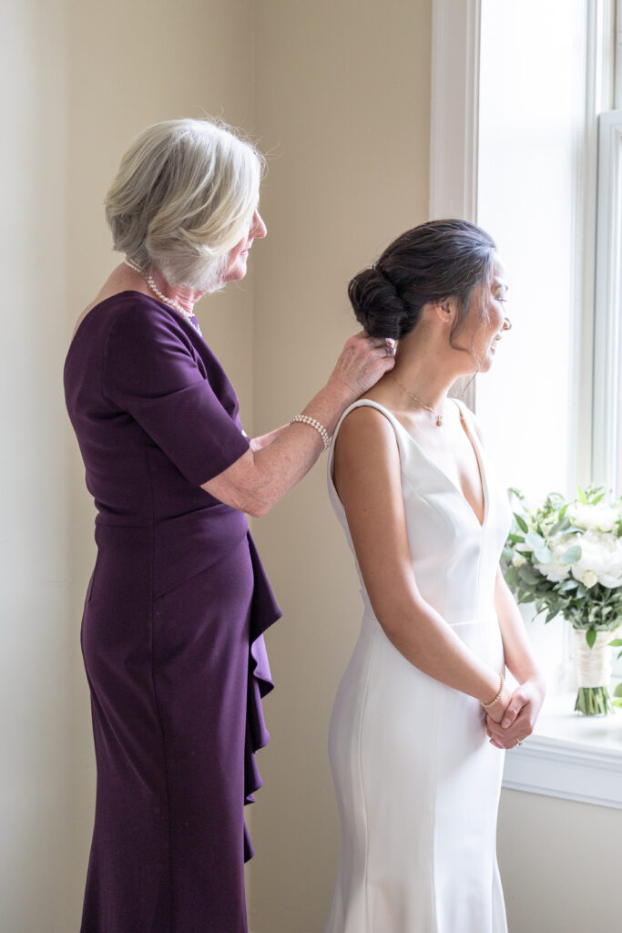 Bride getting ready details - Mom clasping necklace