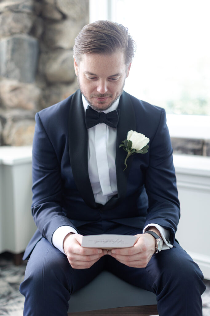 Groom reading a letter inside clubhouse wedding venue