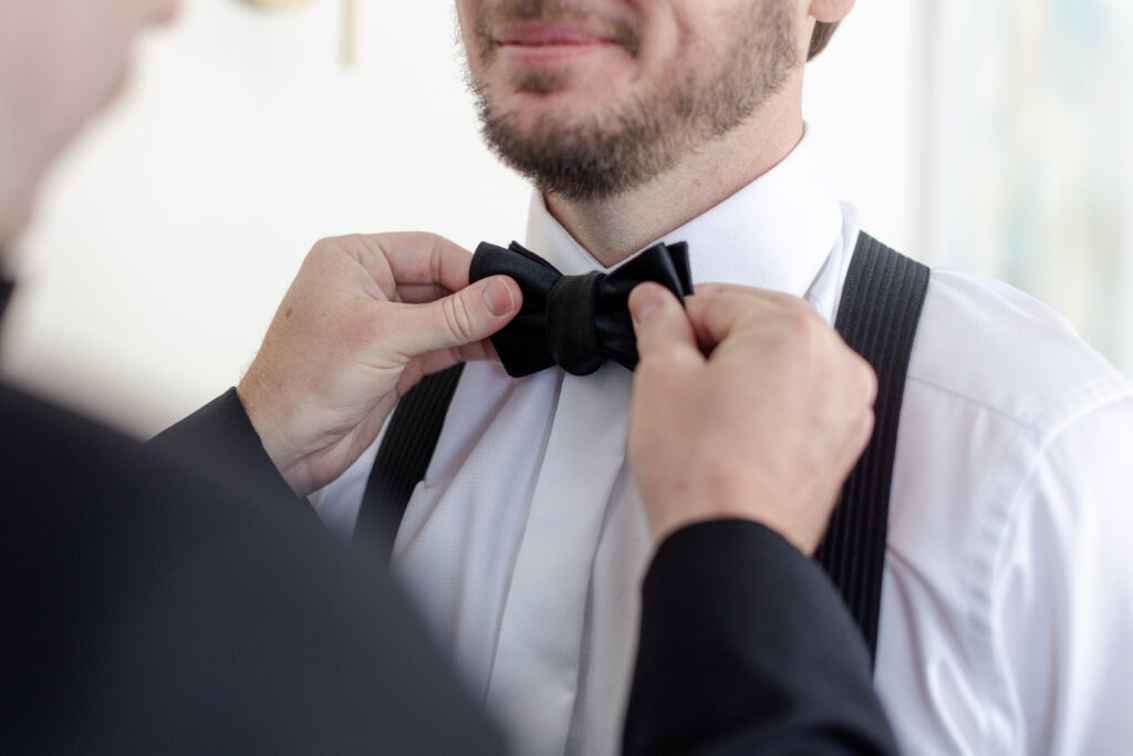 Groom getting ready bow tie close-up detail inside clubhouse wedding venue