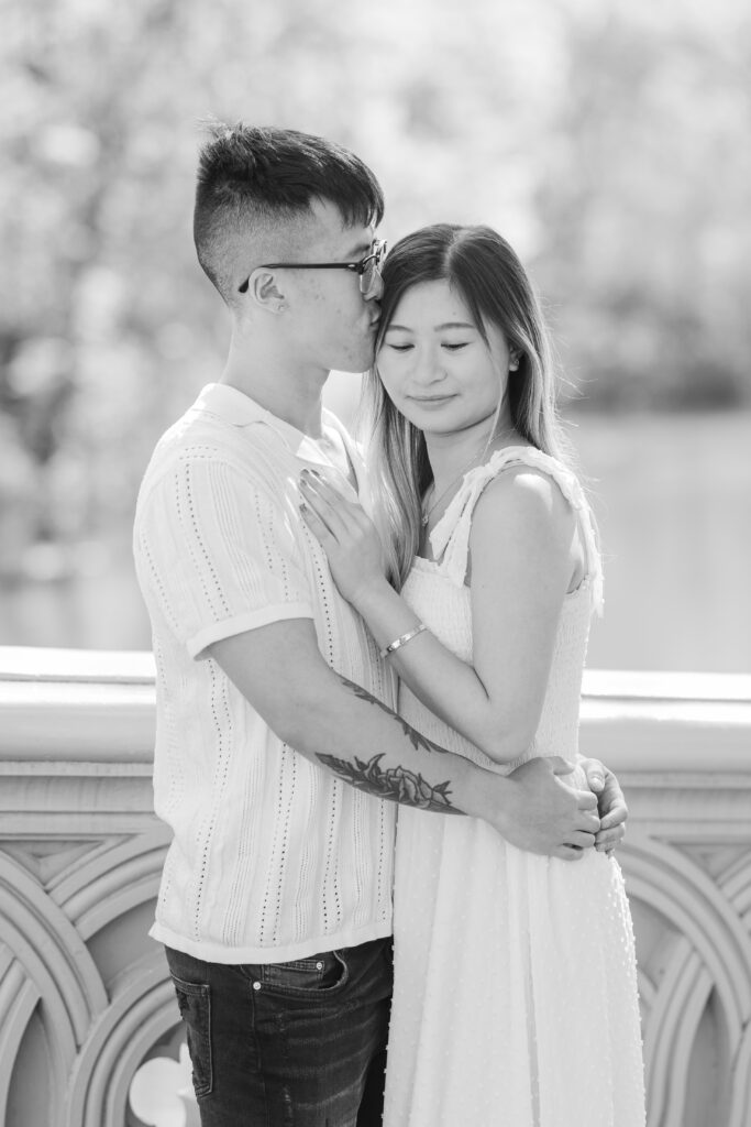 Black and white photo of couple on Bow Bridge against Waterview at Central Park