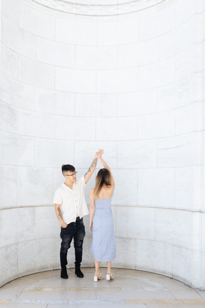 Couple twirling in front of New York Public Library architectural backdrop