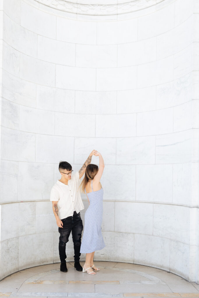 Couple twirling in front of New York Public Library architectural backdrop