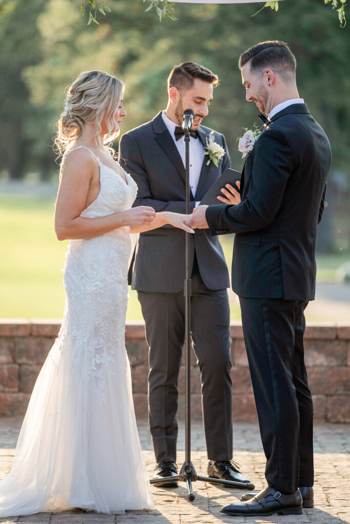 Bride and groom ring exchange during outdoor wedding ceremony