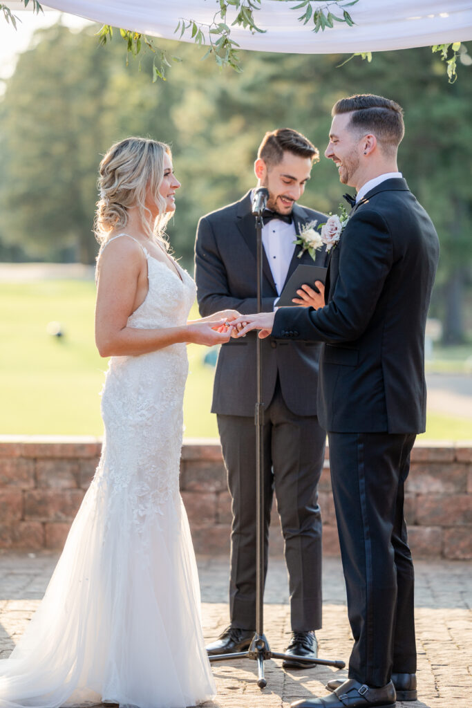 Bride and groom ring exchange during outdoor wedding ceremony