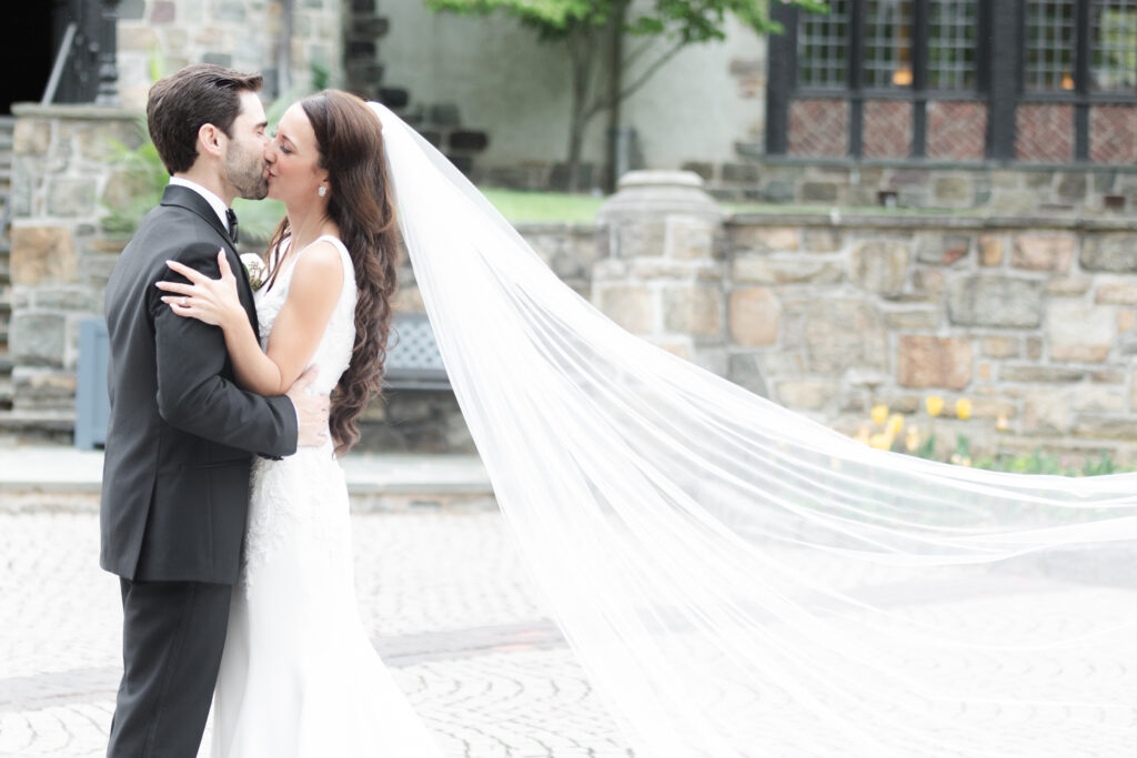 Bride and groom outside of Pleasantdale Chateau with flying veil