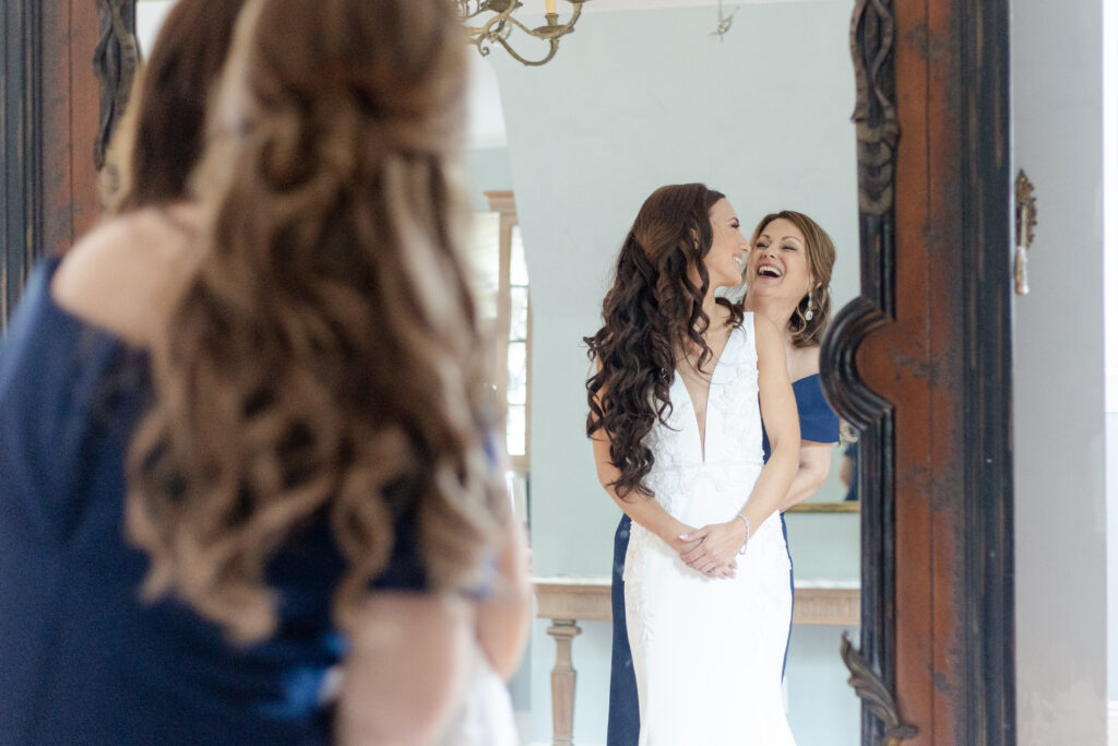 Bride getting dressed with mom in front of classy mirror