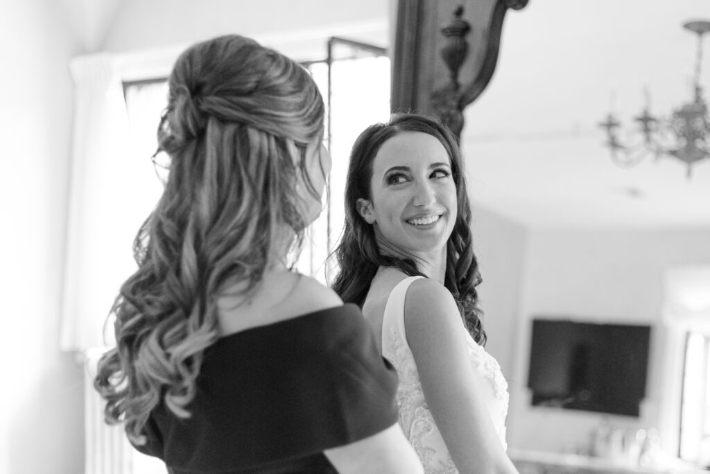 Bride getting dressed with mom in front of classy mirror