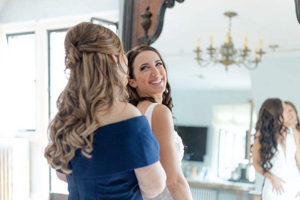 Bride getting dressed with mom in front of classy mirror