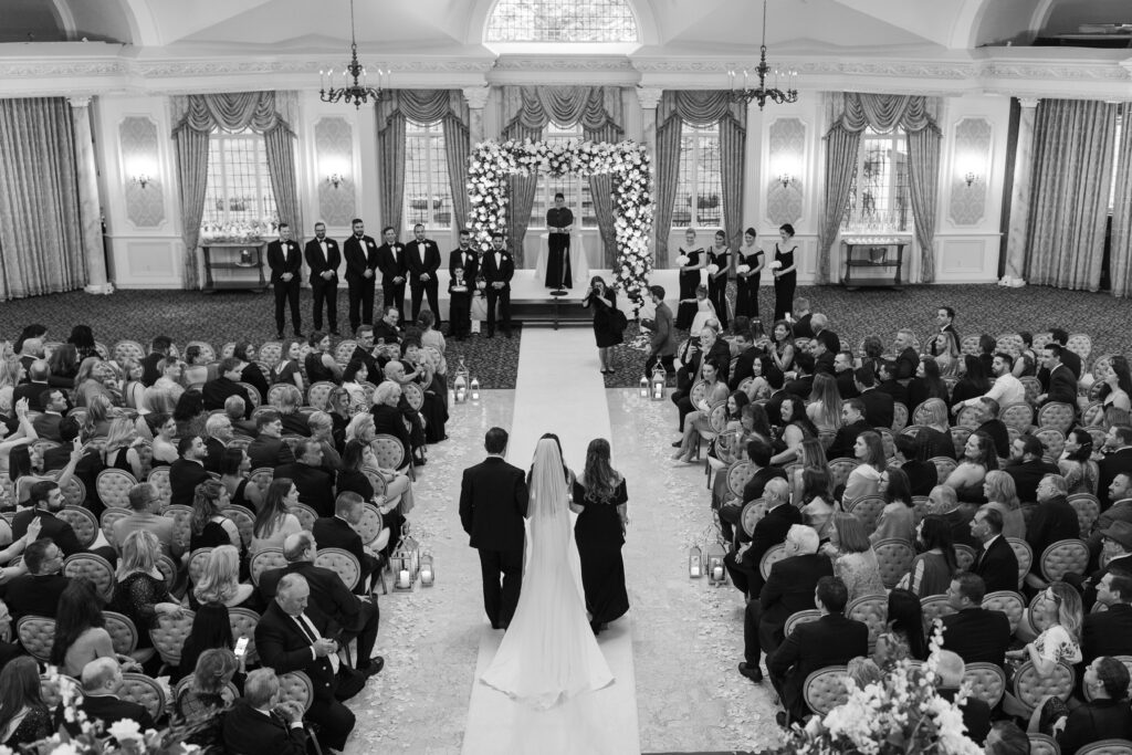 Indoor wedding ceremony with bride walking down the aisle