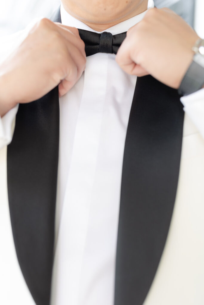 Groom fixing bowtie outside of Chateau Inn and Suites in New Jersey