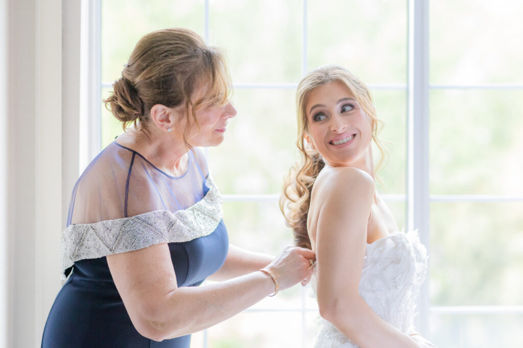 Bride and mom getting wedding gown on