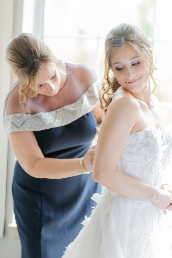 Bride and mom getting wedding gown on