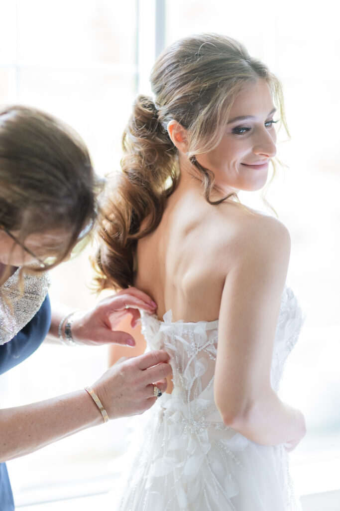 Mom zipping up bride's dress