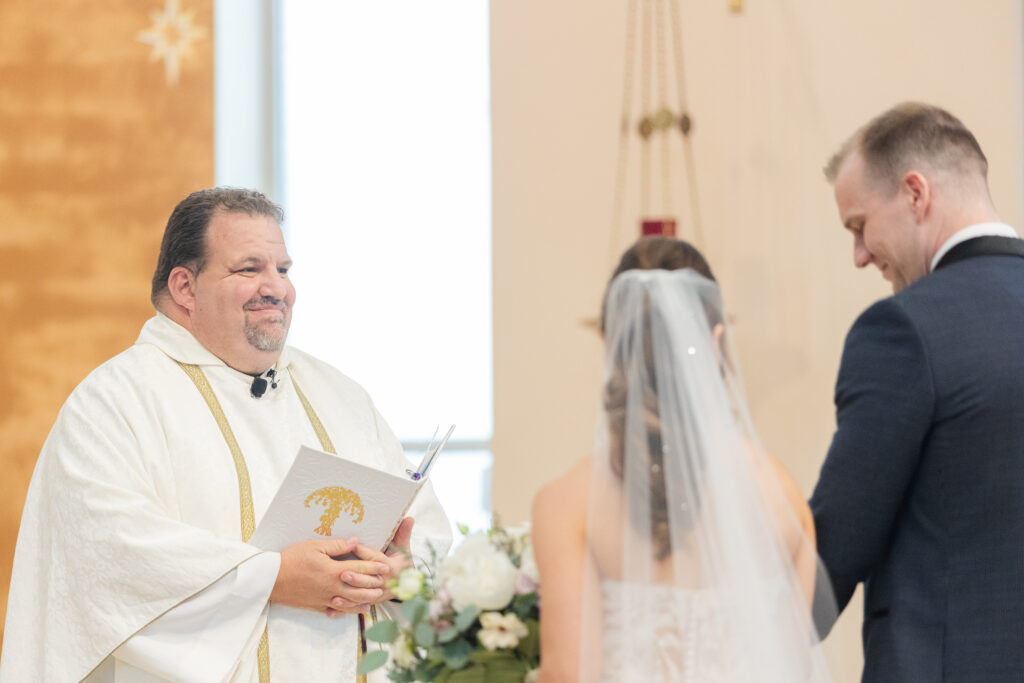 Bride and groom with priest at wedding ceremony