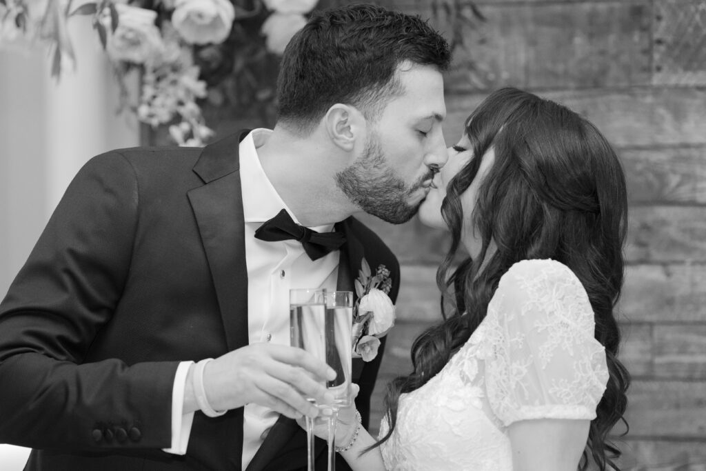 Bride and groom champaign cheers with a kiss in black and white