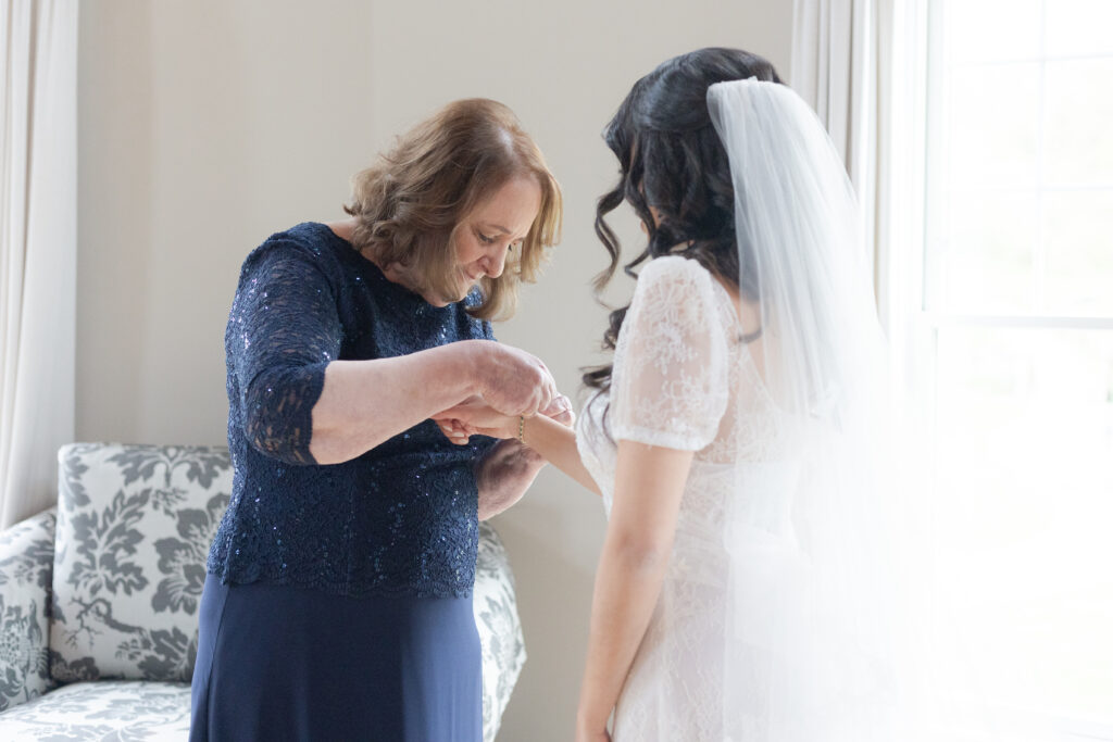 Bride getting necklace on with mom