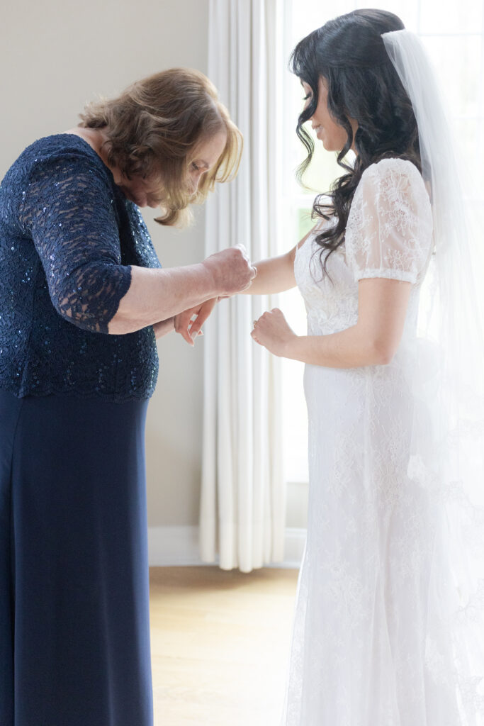 Bride getting necklace on with mom