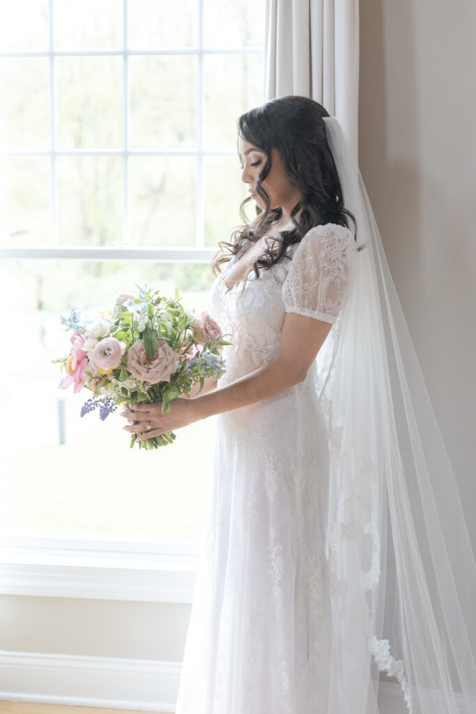 Bride with bouquet in front of window at NJ wedding venue