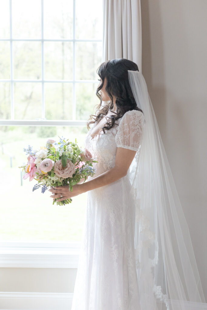 Bride with bouquet in front of window at NJ wedding venue