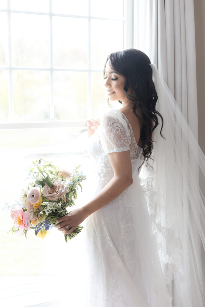 Bride with bouquet in front of window at NJ wedding venue