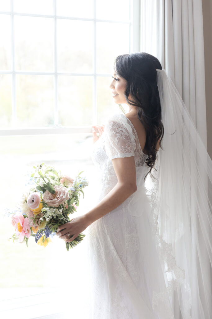 Bride with bouquet in front of window at NJ wedding venue