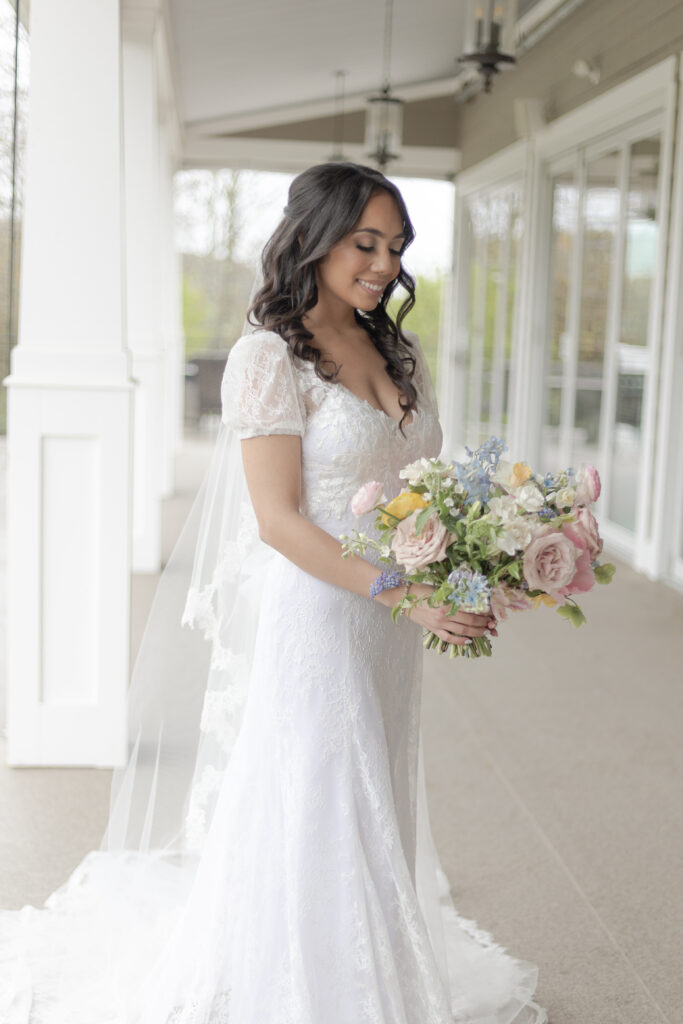 Bride looking at colorful bouquet outside of Bear Brook Valley Wedding Venue