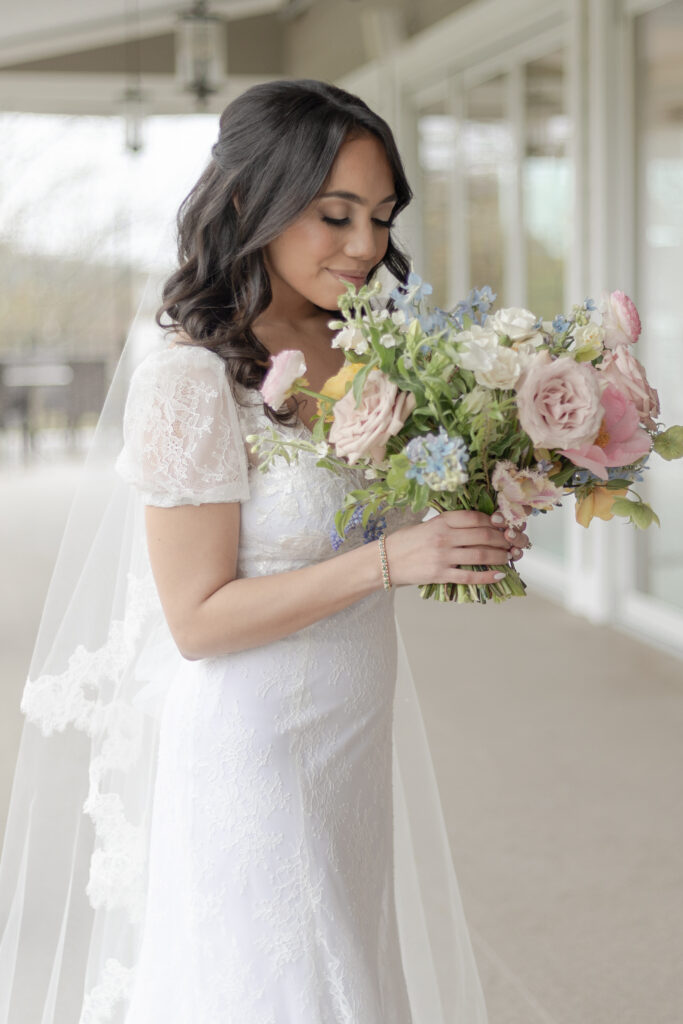 Bride smelling at colorful bouquet outside of Bear Brook Valley Wedding Venue