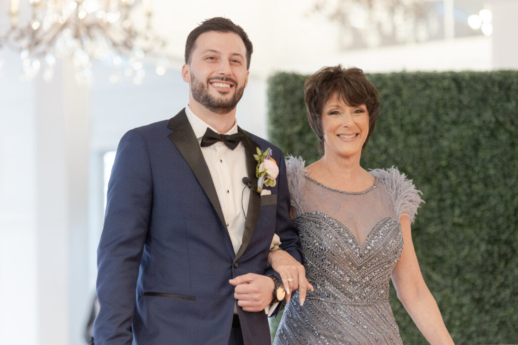 Groom and mom walking down aisle for indoor wedding ceremony