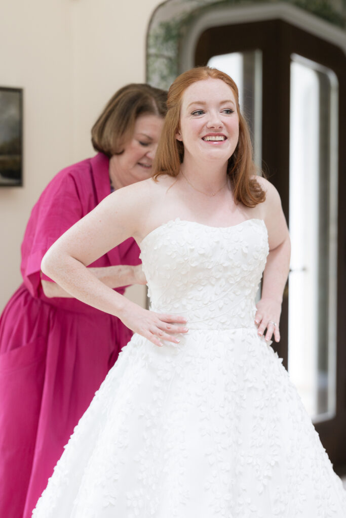 Bride and mom getting wedding dress on