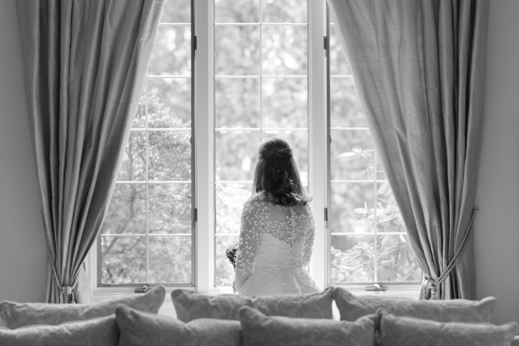 Black and white of bride looking out the window