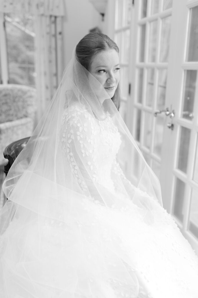 Black and white of bride staring out the window