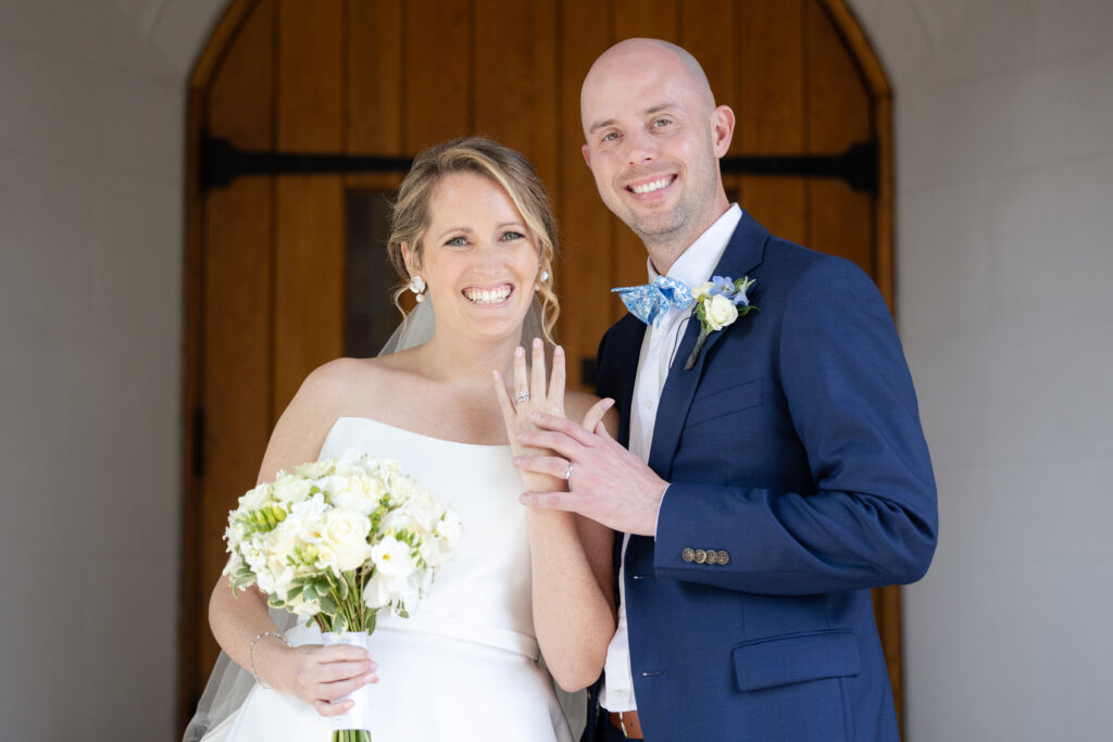 Bride and groom outside of wedding church with just married rings