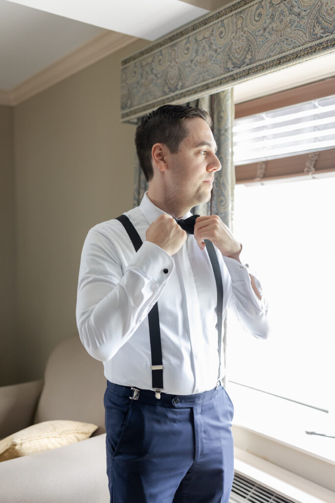 Groom adjusting bow tie inside groom's suite at Madison Hotel Wedding