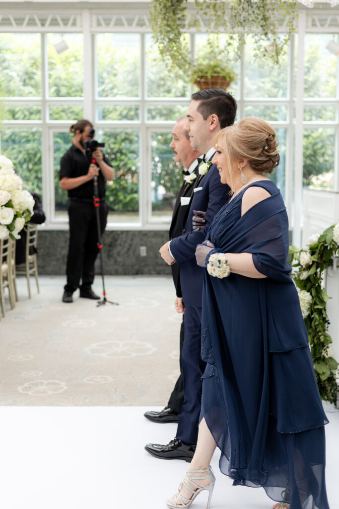 Bride and parents walking down the aisle inside Madison Hotel Conservatory