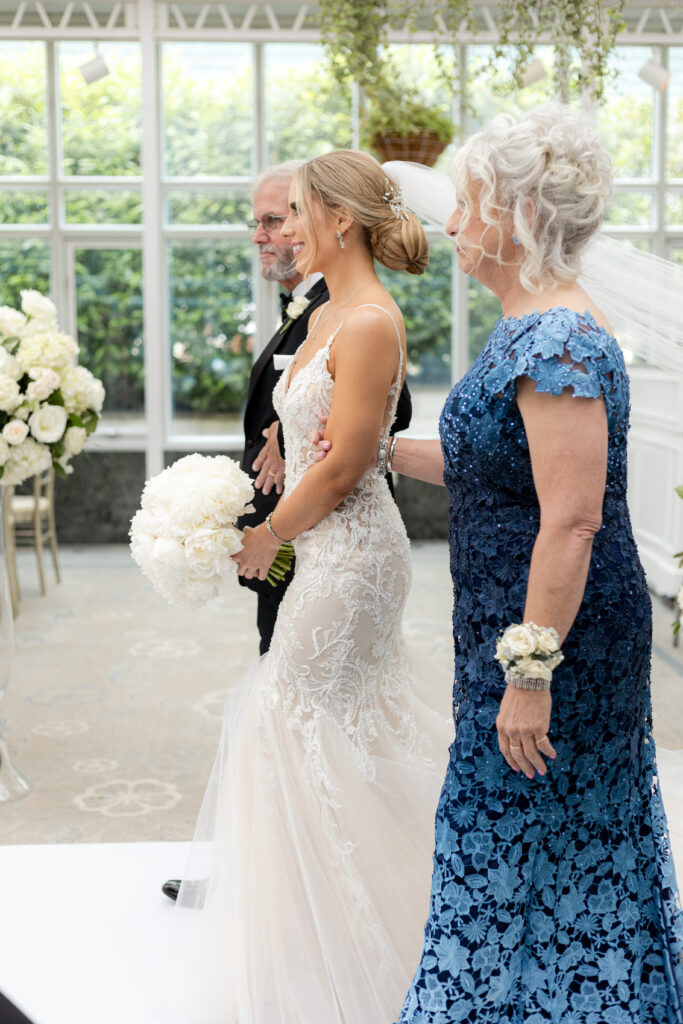 Bride and parents walking down the aisle inside Madison Hotel Conservatory