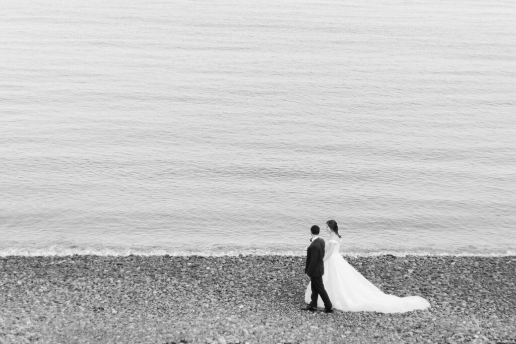 Black and white photos of Bride and groom walking along the beach