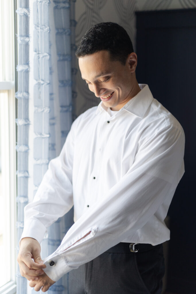 Groom putting on cufflinks at Salem Hotel Waterfront