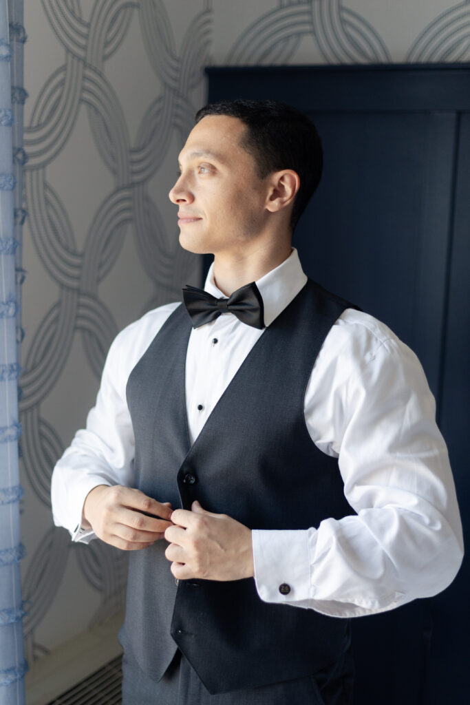 Groom putting on vest at Salem Waterfront Hotel