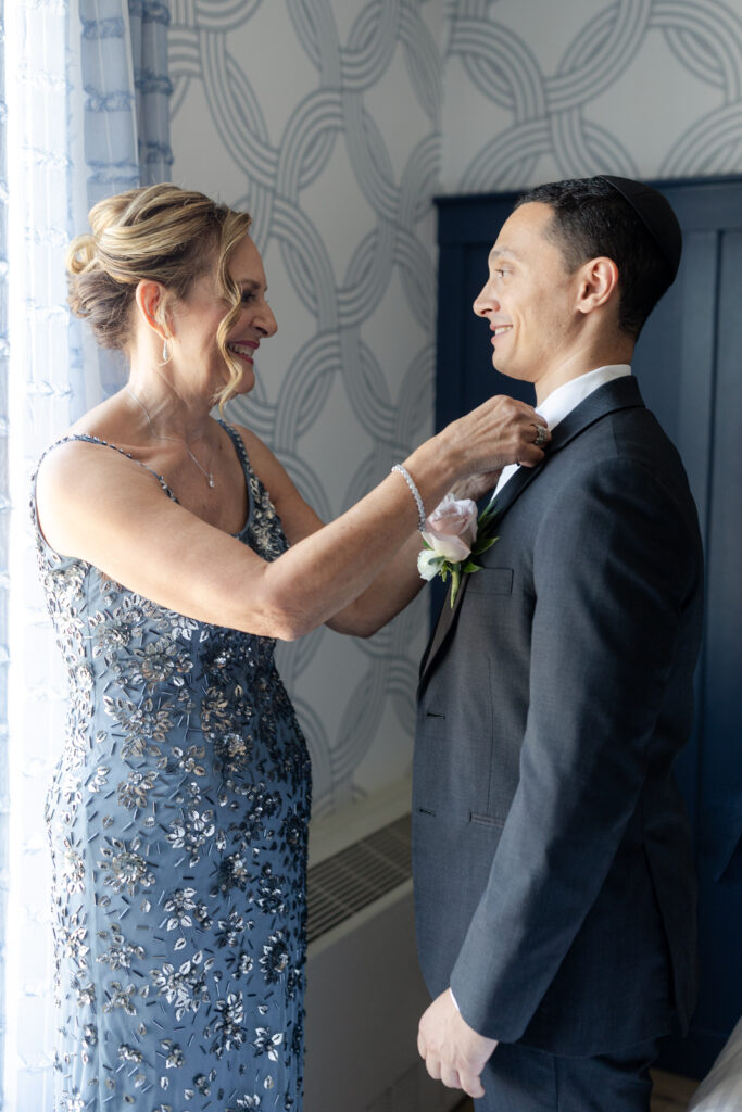 Groom's mom putting on groom's boutonniere at Salem Waterfront Hotel