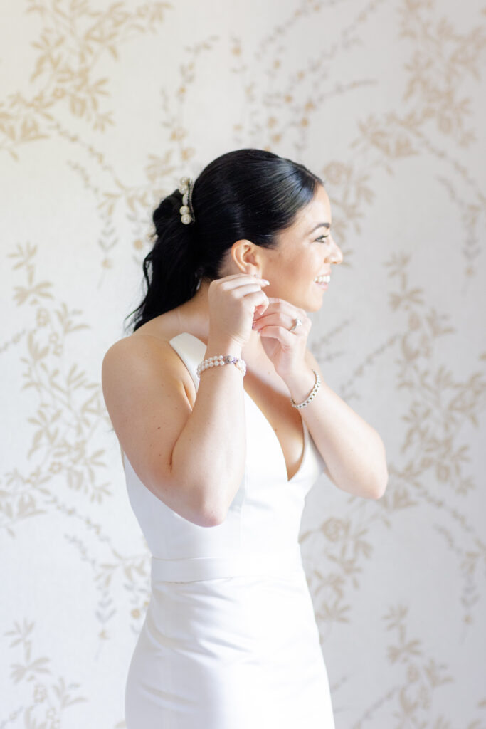 Bride putting on earrings inside NY bridal suite