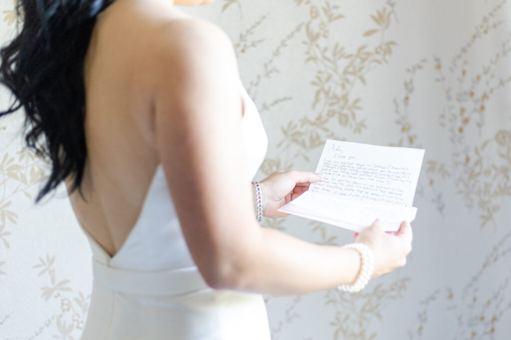 Bride reading groom letter in country golf club bridal suite