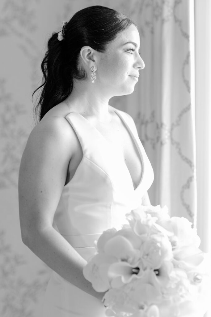 Bride looking out the window with her white bouquet