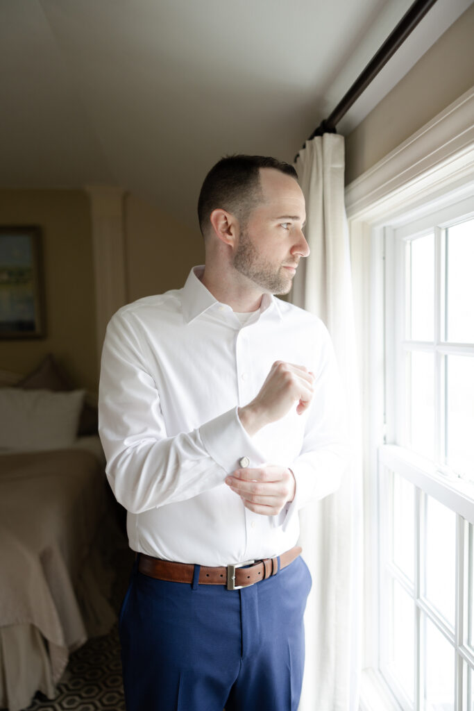 Groom fixing cufflink at Basking Ridge Hotel's suite