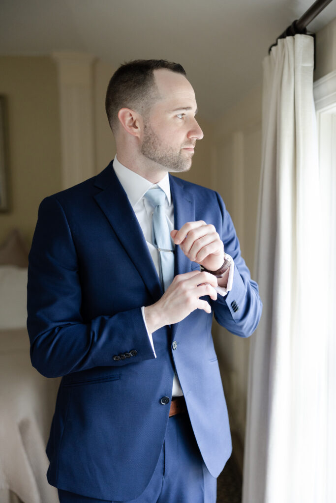 Groom fixing cufflink at Basking Ridge Hotel's suite