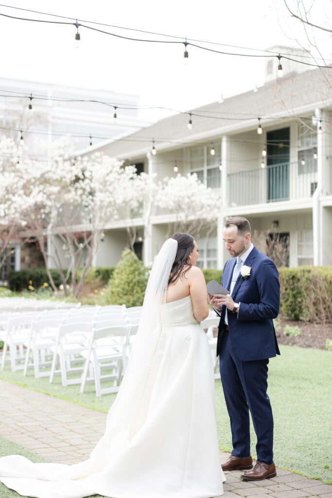 Groom reading private vows to bride outside luxury hotel wedding venue