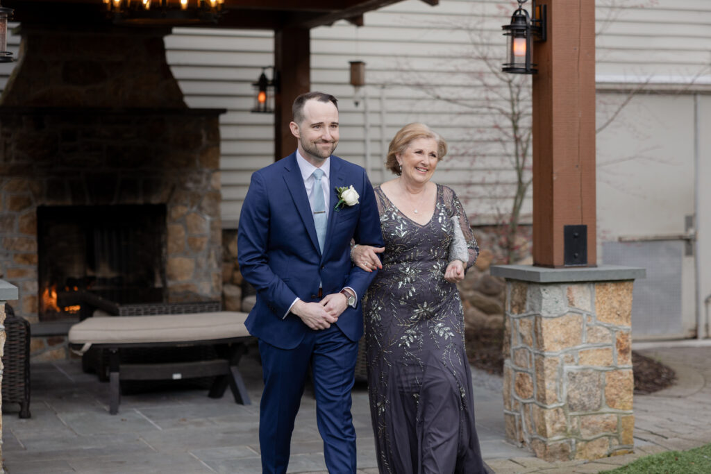 Groom and mom walking down the aisle during outdoor wedding ceremony