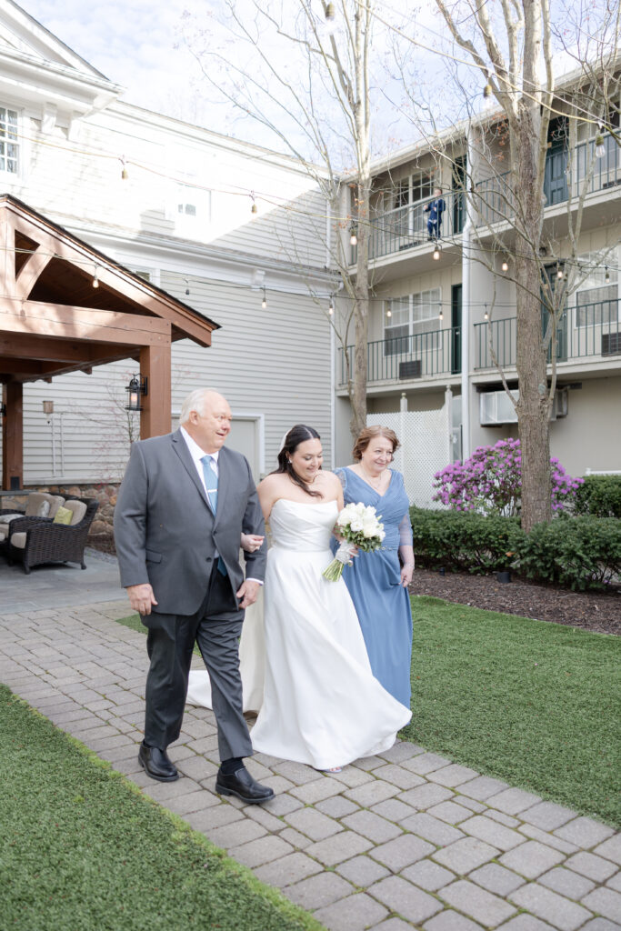 Bride and parents walking down the aisle during outdoor wedding ceremony