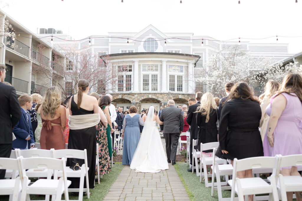 Bride and parents walking down the aisle during outdoor wedding ceremony